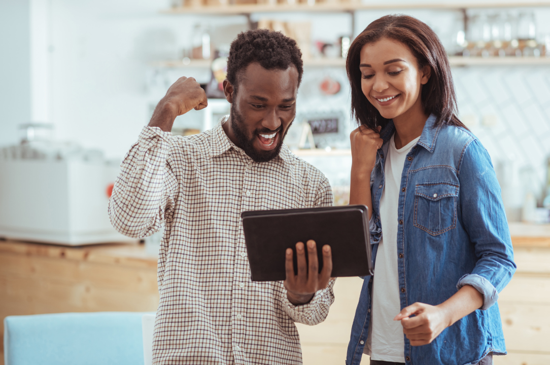 Man and woman looking at ipad with smiles on their faces